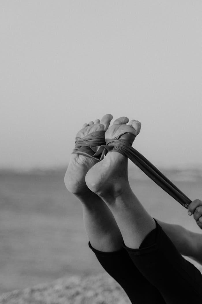 Black and white image of a stretching exercise using a resistance band.